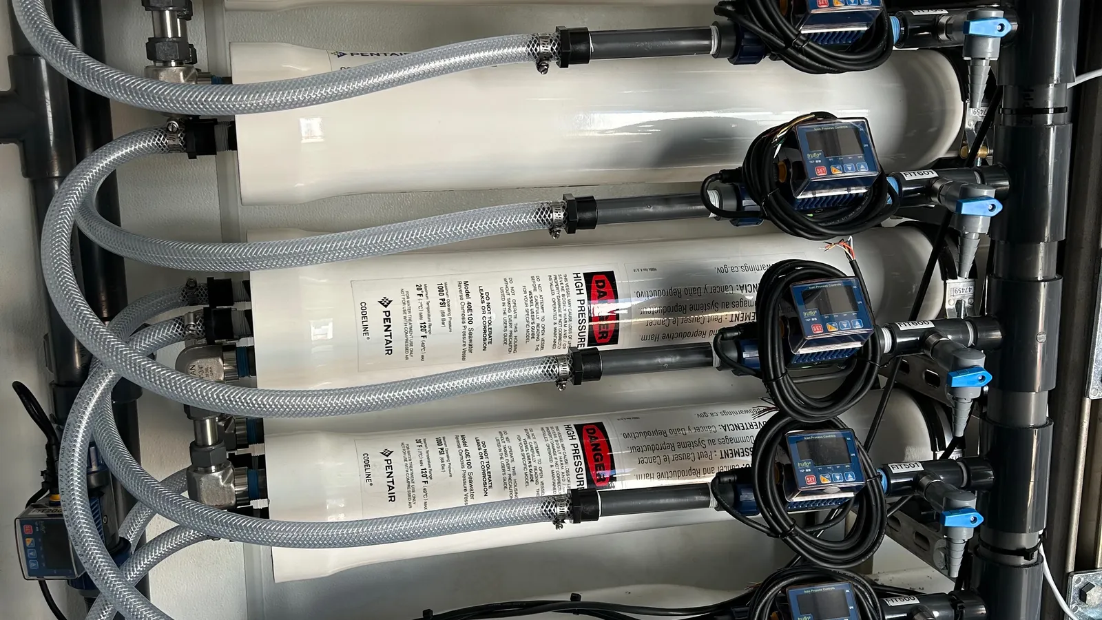 Reverse-osmosis pressure vessels stacked inside a PWR treatment skid, each stage with its own pressure transmitter and flow meter.